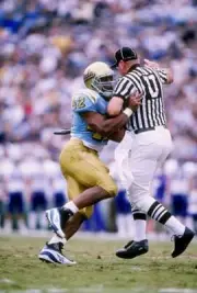 Running back Skip Hicks of UCLA runs into a referee while carring - Old Photo