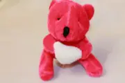 PINK PLUSH LITTLE TEDDY BEAR HOLDING A WHITE HEART THREE INCH HIGH