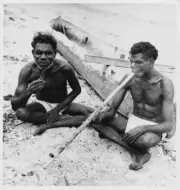 Two Australian Aborigines seated by a canoe an Arnhem Land beach s- Old Photo