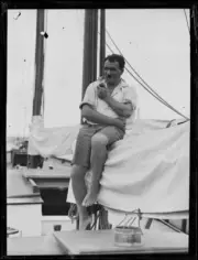 Mr Lee K Murray smoking on the rolled sails of his yacht Day Dream,- Old Photo