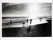 Silhouettes of people running on the beach at sunset circa 1930 Old Photo
