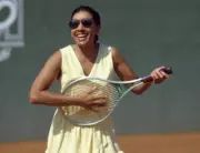 Singer Shirley Bassey plays air guitar on her racket during a ten - Old Photo