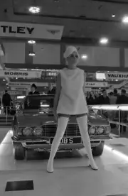 A model poses in front of an Aston Martin DBS 1967 Motor Show Car Old Photo