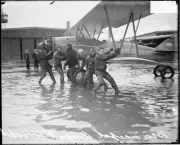 Group Of Men Pulling An Airplane Along A Flooded Airfield At Muni - Old Photo