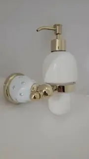 Liquid pumping wall mounted soap dispenser with gold and crystal frame.