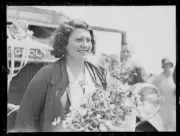Singer Gladys Moncrieff holding a bouquet of flowers in front of a- Old Photo