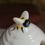 white ceramic honey jar adorned with bees wooden spoon