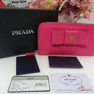 美麗堡outlet精品 PRADA 1M0506金字大蝴蝶結 Saffiano 防刮皮 ㄇ型拉鍊長夾 桃紅色(特價現貨)