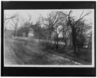 House with white picket fence partially obscured by surrounding trees