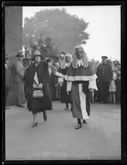 Judge John Harvey wearing justice robes and wig walking with a wom- Old Photo