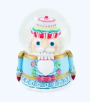Multicolored Pastel Nutcracker Snow Globe Wearing A Cupcake Hat