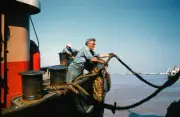 The tugboat Orleans worker throws the rope to tie to the dock, in - 1957 Photo