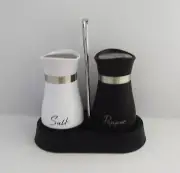 Black and white salt and pepper shakers with clear glass bottom in holder