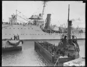 Men on a punt and wharf by the aircraft carrier H.M.A.S. Albatross- Old Photo