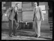 Two men carrying a large box of bank notes being transferred from - Old Photo 1