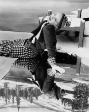 Bette Davis wearing winter clothes and sitting on a mirror which i- Old Photo