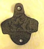 Cast iron wall-mounted bottle opener a star and 2 pistals on top.