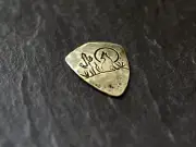 Brass guitar pick in shield shape with howling coyote